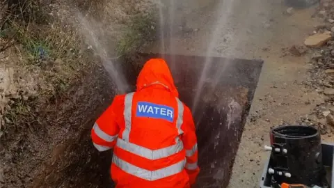 @stwater A Severn Trent engineer fixing a burst pipe as water sprays into the air