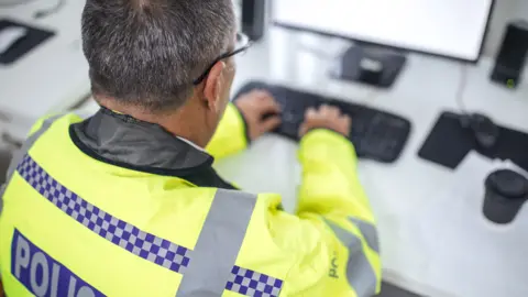 Getty Images One senior traffic warden sitting at the office in front of the computer and writing a report