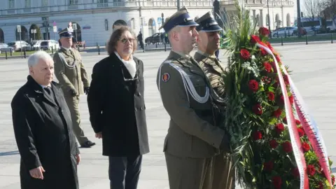 Getty Images Leader of the Polish Law and Justice (PiS) ruling party Jaroslaw Kaczynski (L) lays a wreath at the monument of late President Lech Kaczynski at Pilsudski Square in Warsaw, Poland, on April 10