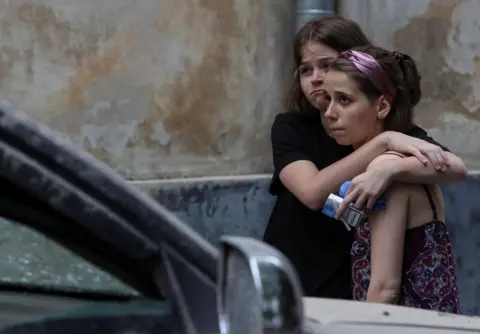 Roman Baluk / Reuters Local residents at a site of a residential building hit by a Russian missile strike in Lviv, Ukraine