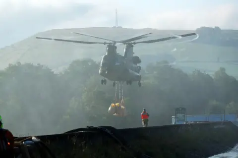 Yui Mok/PA Media Chinook hovers over dam