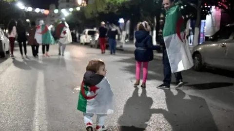 AFP/Getty Images A small child draped in Algeria's national flag celebrates in Algiers. Photo: 2 April 2019