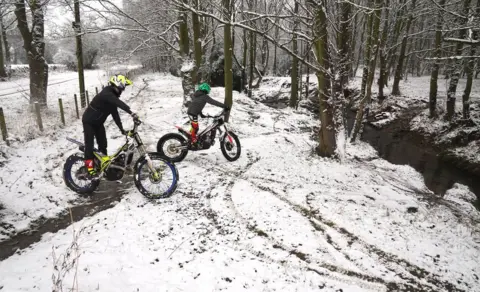 PA/Owen Humphreys Riders take their bikes through the snow near Castleside, County Durham.
