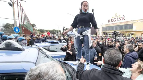 EPA Relatives of inmates protest as law enforcement officers stand outside the Rebibbia prison in Rome, where a riot earlier broke out, 9 March 2020