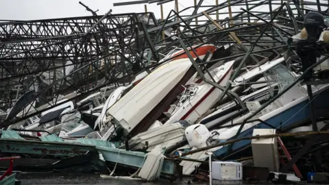 Getty Images A warehouse of boats is damaged at Treasure Island Marina after Hurricane Michael made landfall along the Florida Panhandle, 10 October 2018