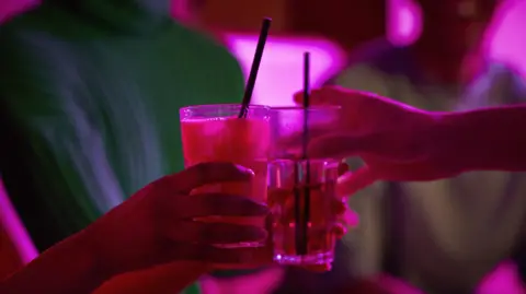 Two drinks at a bar with pink lighting