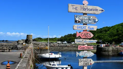 A harbour with small boats and sigs to local stores