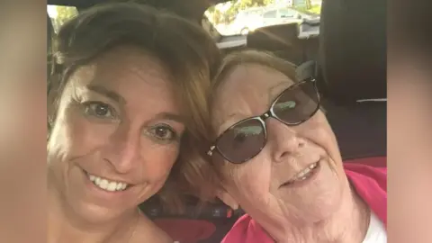 Anabel Sharma A selfie of Anabel Sharma, on the left of the image, with her mum Maria on the right. They are sitting in the front seats of a car, leaning towards each other and smiling at the camera. Maria is wearing brown sunglasses.