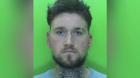 Nottinghamshire Police A mugshot of a man with dark brown hair and tattoos and piercings