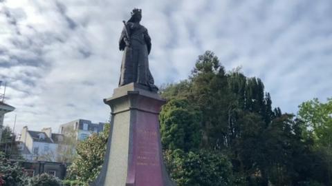 A statue of Queen Victoria which has been defaced with pink paint.
