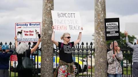 Zac Goodwin/PA Protesters held up placards outside the racecourse before and during the even