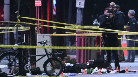 Getty Images A forensic investigator takes photos behind a police tape blocking off a crime scene with evidence markers seen on a sidewalk on 17th and Pennsylvania Ave near the White House in Washington