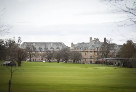 PA Media Grass playing fields with a three storey stone building with a slate roof in the background