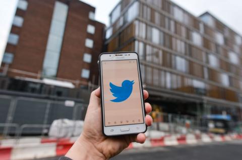 Hand holding smartphone with twitter logo, outside Twitter headquarters in Dublin