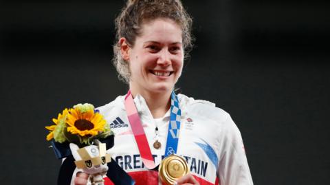 Kate French holding her gold medal and a bunch of sunflowers at the 2020 Tokyo Olympics