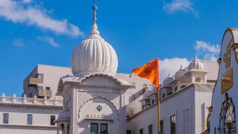 Getty Images A white gurdwara building with a triangular orange flag flying from a flagpole 
