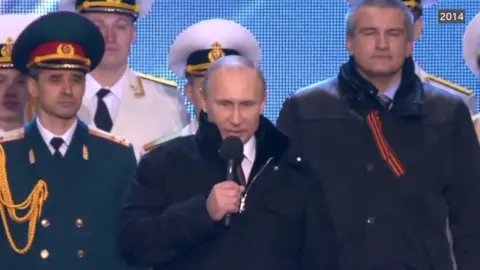 Putin speaks at a 2014 rally surrounded by Russian military officers
