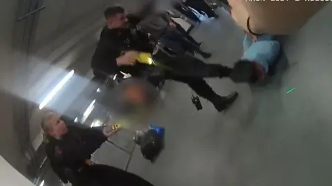 PA Media Video grab image issued by the Crown Prosecution Service (CPS)
from police body worn camera of footage of the alleged assault of three police officers at Manchester Airport which has been played to jurors at Liverpool Crown Court. 