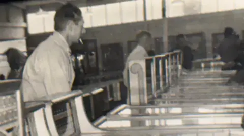 Gareth Cammack Bill Cammack (Gareth's grandfather) tends to the machines. Bill has a cigarette in his mouth. He is standing in front of a line of gaming machines.