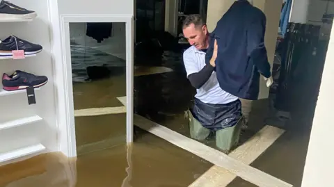  Brendan Digney Paul McCartan waded through flood water to salvage stock in his store last October