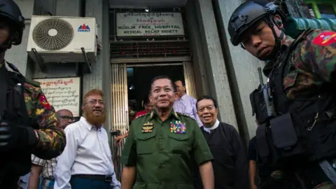 Getty Images General Min Aung Hlaing walks towards the camera surrounded by officials and police. 