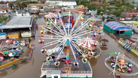 Aerial view of a flooded amusement park including a large ferris wheel.
