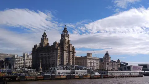 Liverpool waterfront, showing urban regeneration. Royal Liver building, Cunard Building and Port of Liverpool building (Three Graces) with Pier head ferry terminal, seen from a ferry in the Mersey