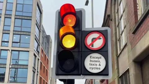 A close-up of a set of traffic lights in Preston. The red and amber lights are illuminated.