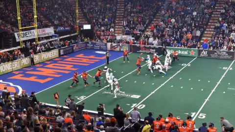 Getty Images An indoor American football game, with two teams competing - one in mostly white and the other in orange and black.