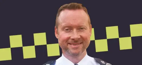 Bedfordshire Police Chief Constable Trevor Rodenhurst looking at the camera, in front of a police stripe