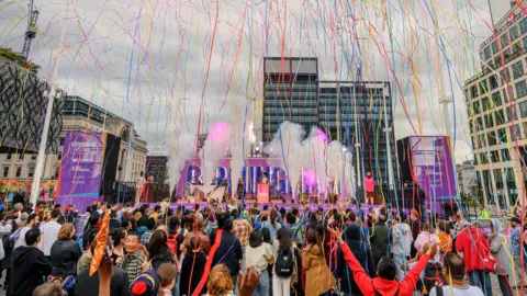 Katja Ogrin Birmingham Festival 23 opening event, featuring a crowd of people in front of a stage, with streamers pouring down