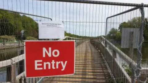 National Trails A footbridge boarded up with a red no entry sign attached to the metal railing.