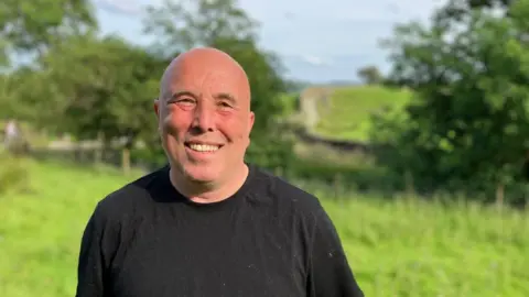 Andre Rostrant, a man wearing a black t-shirt smiles at the camera