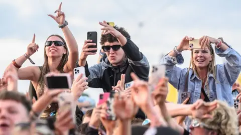 Getty Images A music festival crowd, featuring three fans sitting on shoulders.