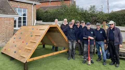 Chris Hockley Men's Shed group stand by climbing frame