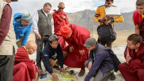 Rolex/ Stefan Walker Group of people including Sonam Wangchuk gathering around ice stupa plans