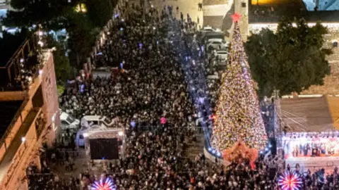 Crowds gathered in front of a Christmas tree in Bethlehem's Manger Square