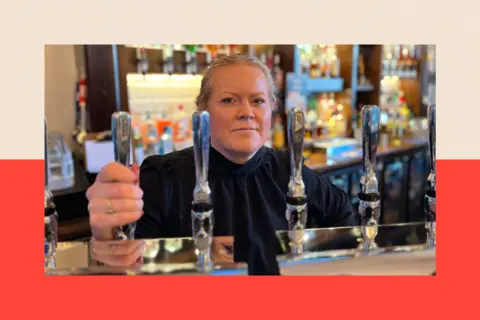 Iona Macdonald behind a bar holding a beer tap