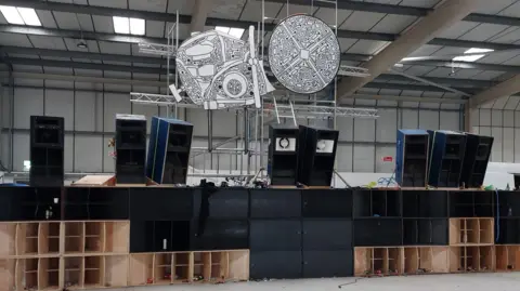 Cambridgeshire Police Speakers are on a stage in part of an industrial building and artworks are suspended from the ceiling