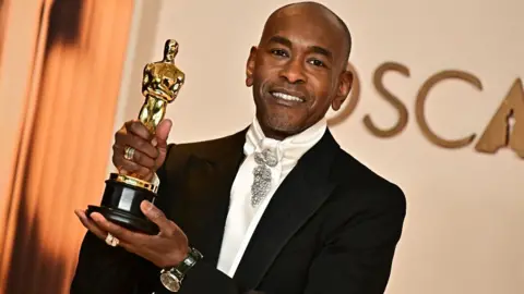 Getty Images El diseñador de vestuario estadounidense Paul Tazewell posa en la sala de prensa con el Oscar para el mejor diseño de vestuario para 