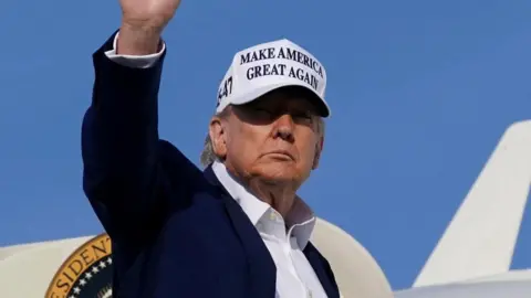 Donald Trump boards Air Force One, holding up his hand