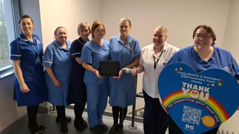 A group of nurses are holding a bladder scanner, one is holding a big sign saying Thank you.