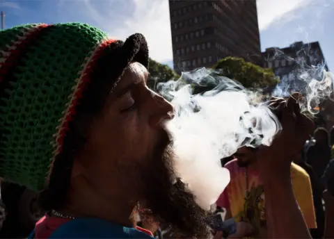 AFP A man smokes marijuana out of a bottle-neck pipe, joining about 1500 people as they protest in front of the South African Parliament, to call for the complete legalisation of Cannabis or Marijuana in South Africa, on May 5, 2018, in Cape Town