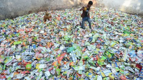 Getty Images A boy searches for food in polythene packets at a roadside in India