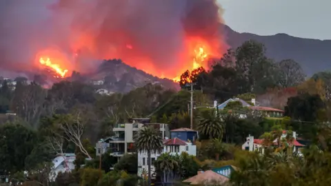 Getty Images A massive fire burns on a hill and the buildings below.