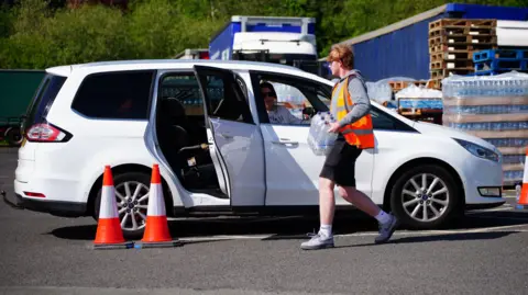 PA Bottled water being put in a car by a man