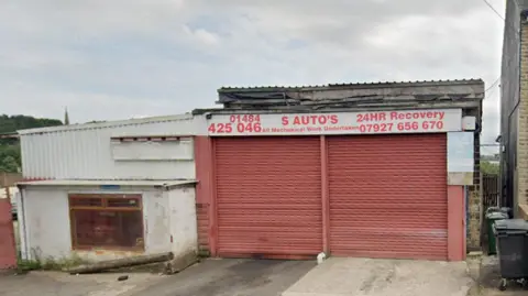 Google Maps image showing the outside of S Autos garage on Bulay Road in Huddersfield, with two large red garage doors and offices in a white building to the left.