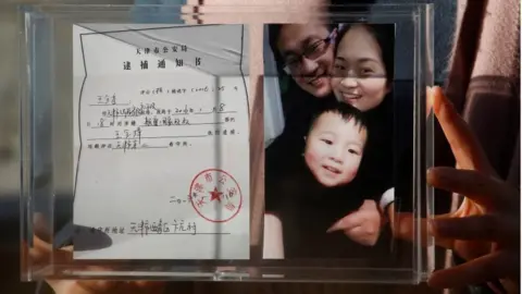 Reuters Li Wenzu, the wife of prominent Chinese rights lawyer Wang Quanzhang, holds a box with a family picture and her husband's detention notice, before shaving her head in protest in Beijing, China