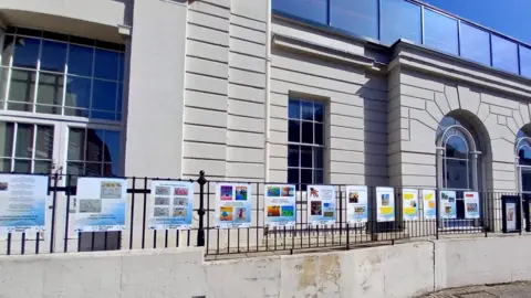 Herts Welcomes Refugees St Albans Museum + Gallery with images from the display attached to its outside railings