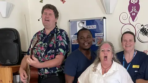 Marcus Brown with a guitar singing with care home staff